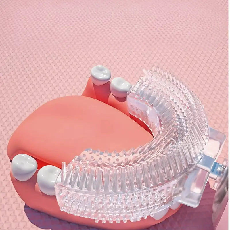 Transparent U-shaped kids toothbrush head placed on a pink dental model showing teeth cleaning coverage.